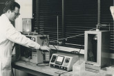 Kurt Sch?rf, staff member, at the vacuum evaporation plant used for gold-coat source mounts to eliminate static electricity. April 1964.  Please credit IAEA  