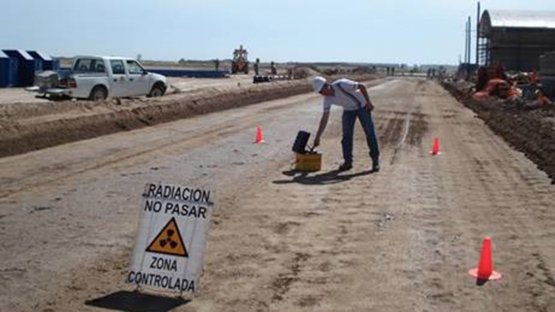 A regulator inspects a nuclear gauge used on pavement to assess quality and density