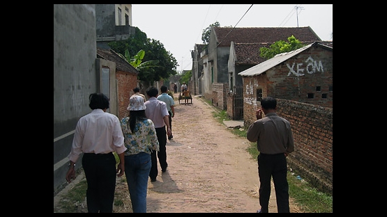 Photo 1 of 15 : The village streets of Thanh Gia in north Vietnam's rice-rich Red River region.  Families in this small hamlet of Bac Ninh Province have been living off the land and rice farming for centuries.  As a mule-drawn cart approaches, a painted sign promoting 'Xe Om' -- or motorbike taxi -- suggests a more modern road ahead. 