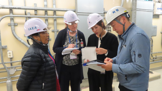A group of four people with hard hats reviewing documentation in an industrial area indoors. 