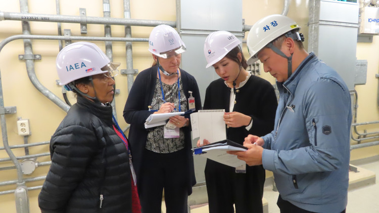 A group of four people with hard hats reviewing documentation in an industrial area indoors. 